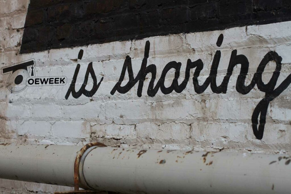 Photo of brick wall with a graffiti saying "is sharing".